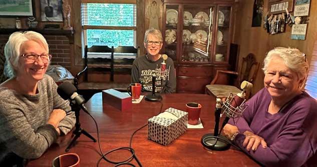 3 women sitting in front of microphones at a dining room table